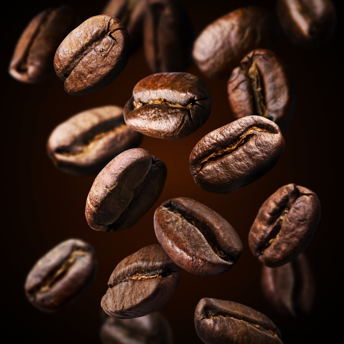 Roasted coffee beans floating in mid-air against a solid black background, showcasing their rich dark brown color and textured surfaces.
