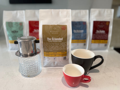 Highest Good The Grounded coffee bag in front of the full Highest Good range, with a phin filter