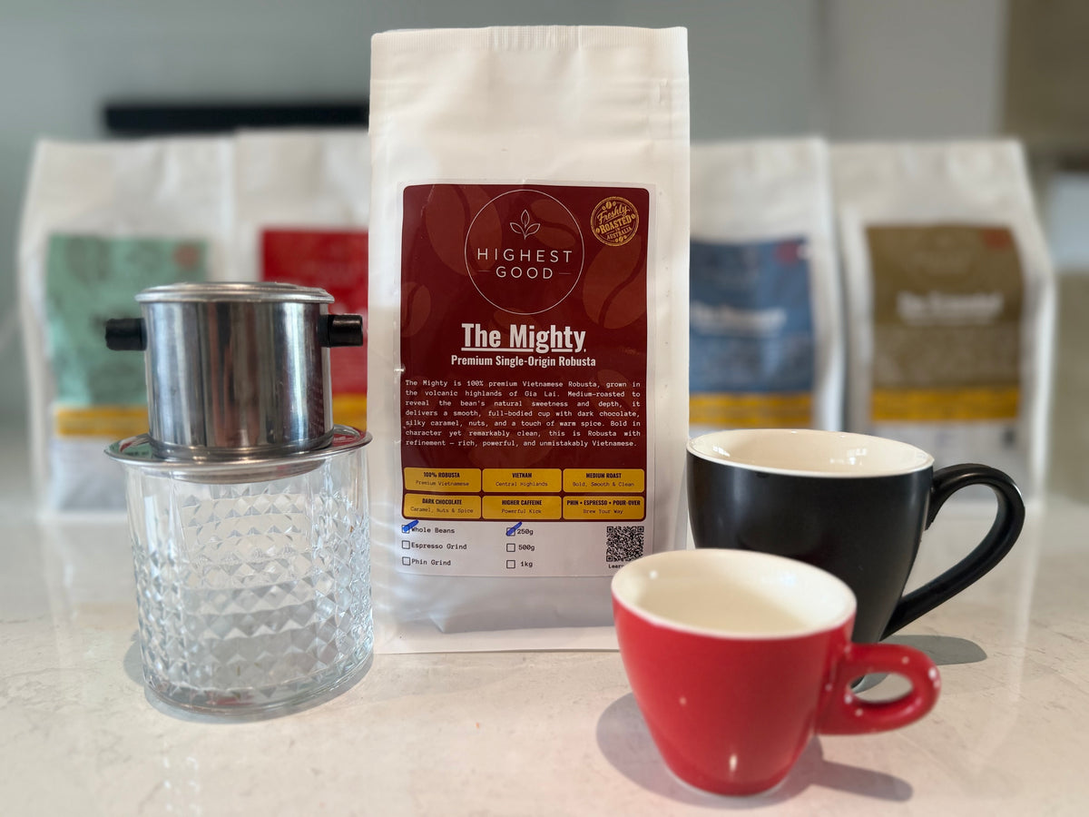 Highest Good The Mighty coffee bag in front of the Highest Good range, with a phin filter and cups