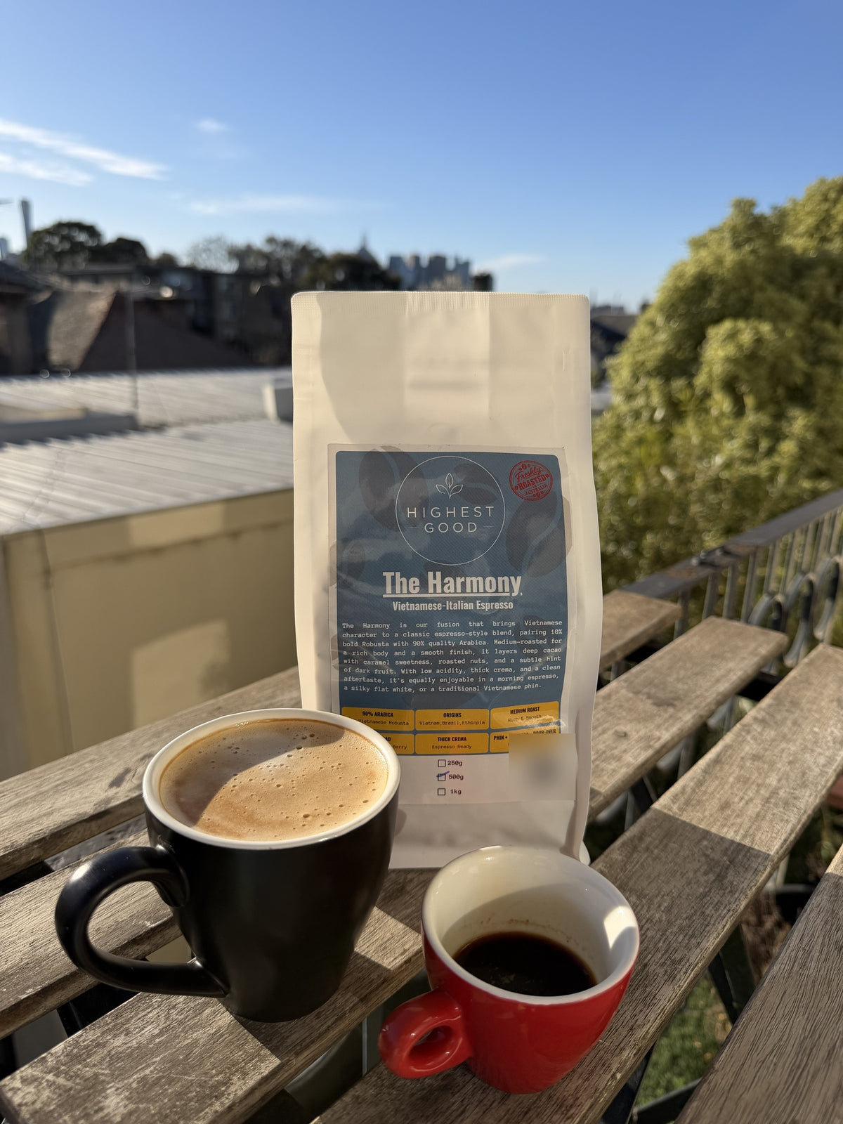 Highest Good The Harmony espresso blend coffee beans with a latte and espresso on a sunny balcony