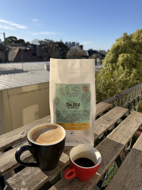 Highest Good The Vital medium roast Vietnamese coffee beans with a latte and espresso on a sunny balcony